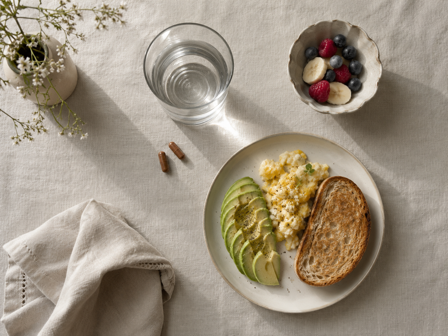 Two FEMPRIMAL capsules beside water and a healthy breakfast